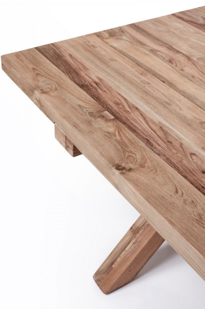 La table à manger Finca de Manufactori, détourée de son environnement, dévoile l’élégance de son design minimaliste. Son plateau rectangulaire, fabriqué en teck recyclé, présente des finitions impeccables qui accentuent la beauté naturelle et chaleureuse du bois. Le piètement en croix, à la fois stylisé et robuste, confère à la table un caractère distinctif tout en garantissant une stabilité parfaite.