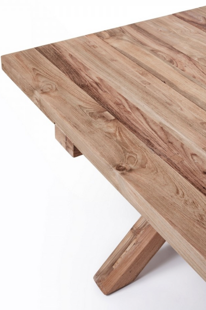 La table à manger Finca de Manufactori, détourée de son environnement, dévoile l’élégance de son design minimaliste. Son plateau rectangulaire, fabriqué en teck recyclé, présente des finitions impeccables qui accentuent la beauté naturelle et chaleureuse du bois. Le piètement en croix, à la fois stylisé et robuste, confère à la table un caractère distinctif tout en garantissant une stabilité parfaite.